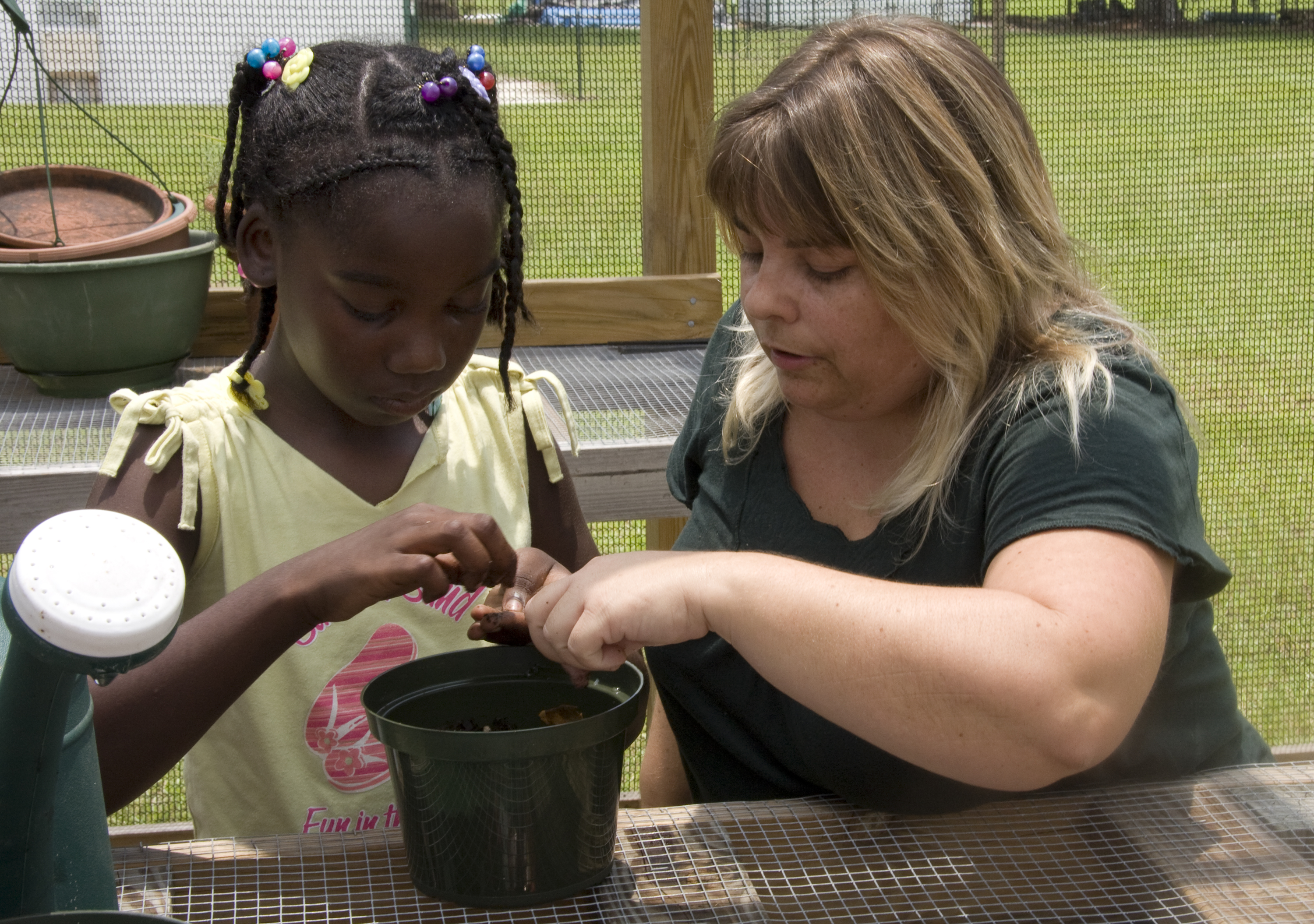 Adult showing youth how to pot plants