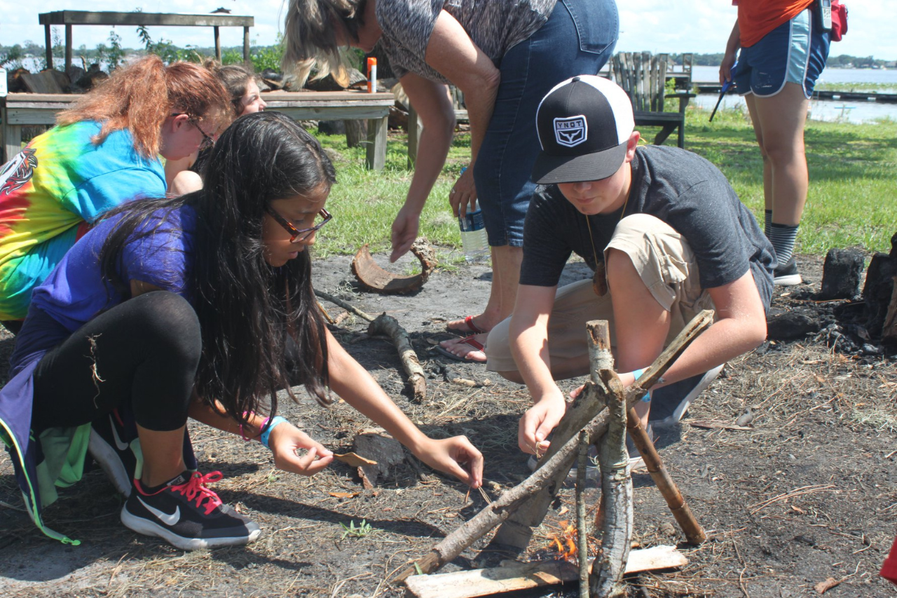 Group of youth lighting a camp fire