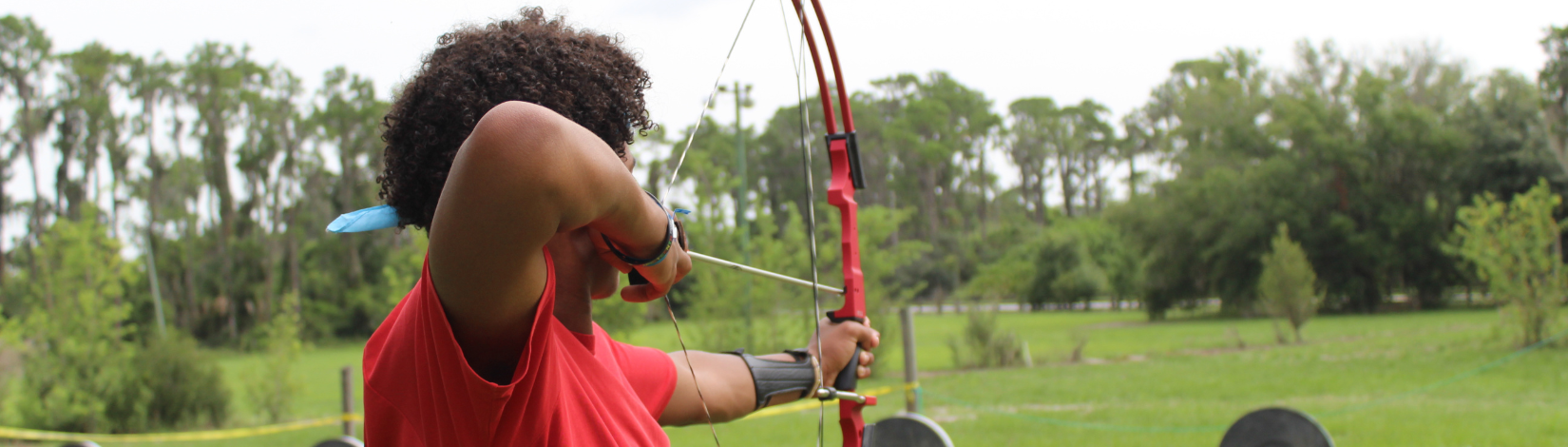 Banner image of youth participating in an archery match