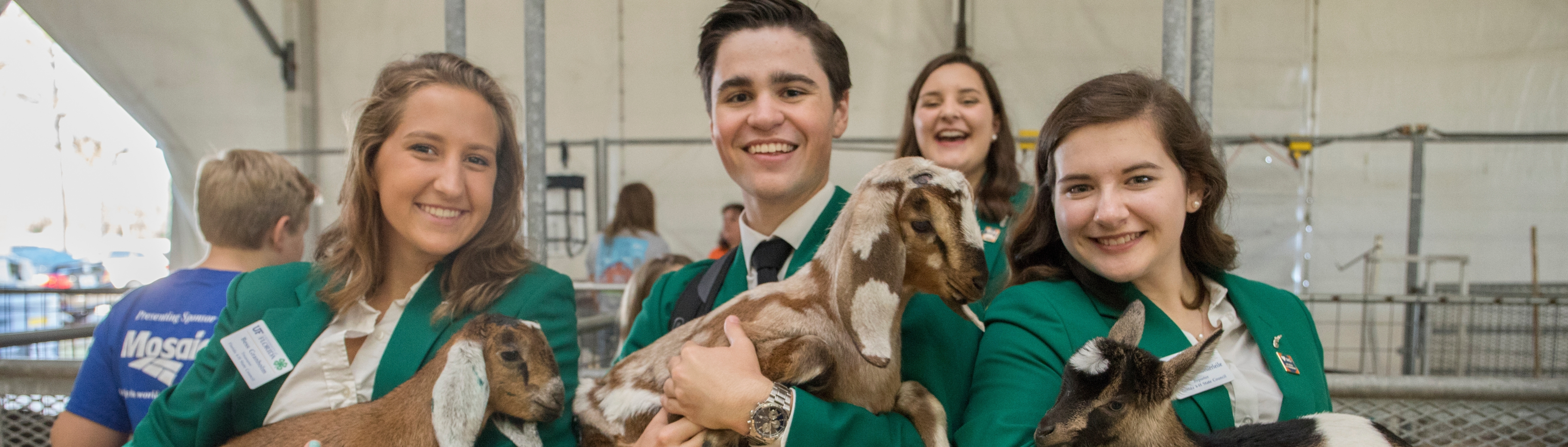 3 youth at the state fair holding baby goats