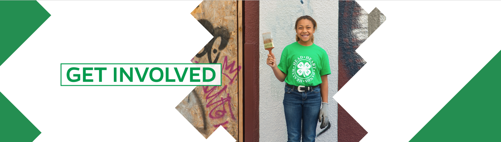 Volunteer 4-H youth smiling with paint brush.